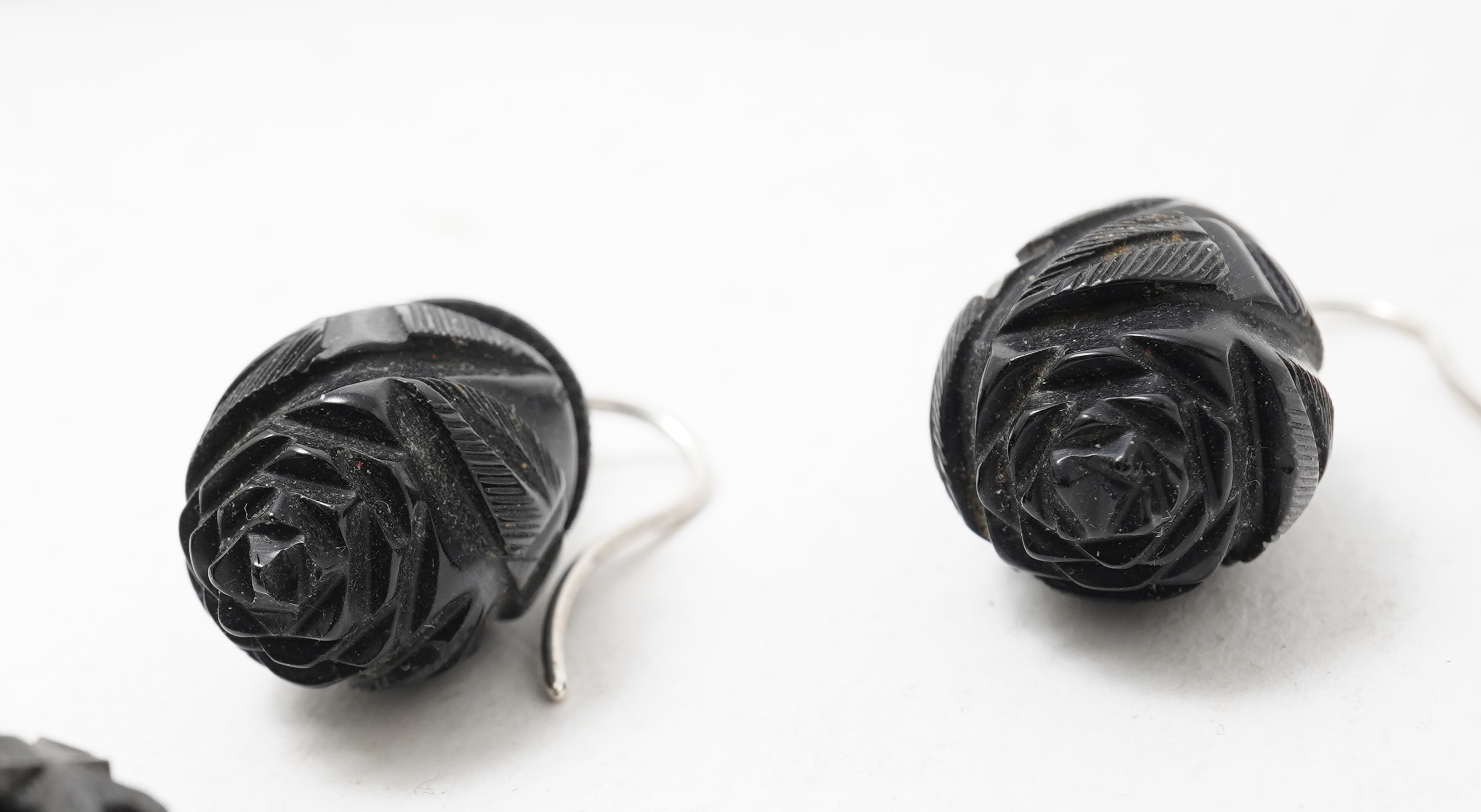 A collection of jewels, comprising: a moulded bog oak brooch depicting a hand holding a posy, length 7.4cm; a carved jet brooch depicting a Gothic ruin, possibly part of Whitby Abbey; a necklace composed of polished pane